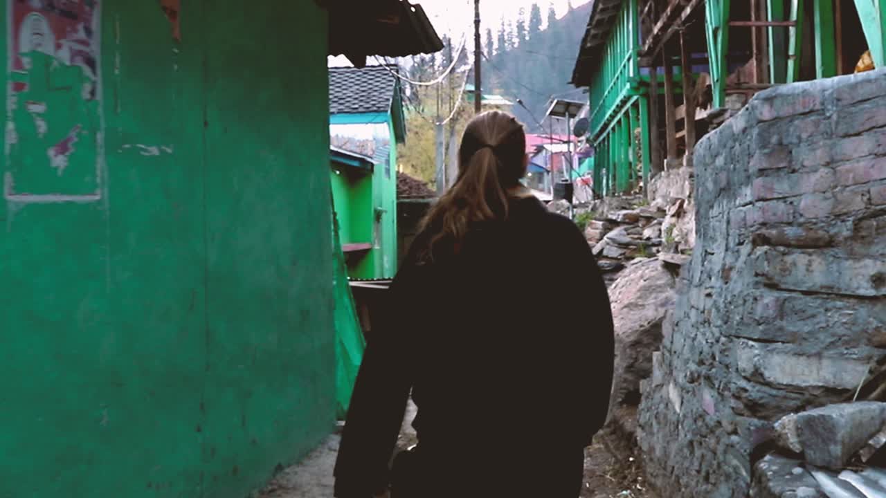 Woman walking through a narrow alley in a remote village in the Indian Himalayas - Tosh, Parvati Valley -  Himachal Pradesh, Northern India