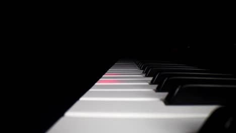 low profile wide angle macro of electronic keyboard - static shot of keyboard as the song assist lights the keys a red glow, then moving backwards slightly as song continues to play