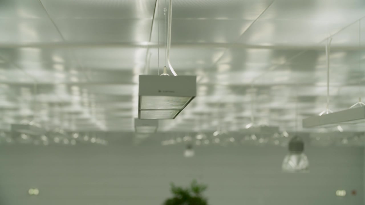 Modern ceiling lights in office interior with reflection on metallic grid ceiling panels