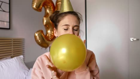 birthday girl blowing a gold balloon