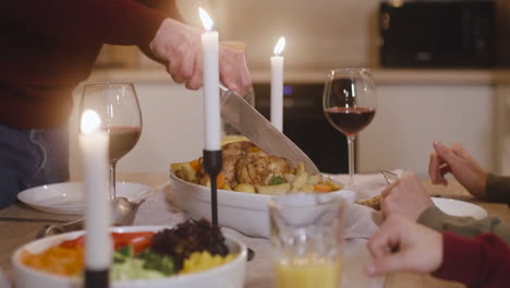 camera focuses on man's hands cutting the turkey in christmas family dinner