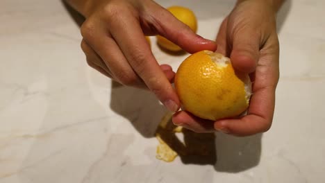 Hands peeling an orange on a countertop