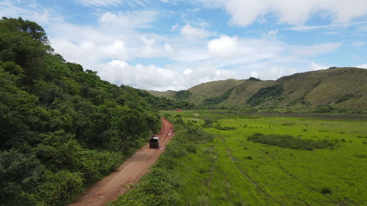 남미 정글의 경사면과 푸른 계곡 사이의 흙길에 있는 트럭의 공중 전망