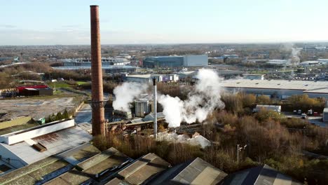 pilkington glass factory warehouse buildings aerial view zoom in towards smoking industrial facility