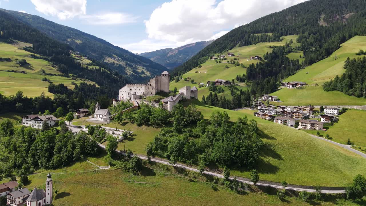 Vista aerea di un drone, castello medievale su una collina verde con villaggio alpino, Heinfels Austria