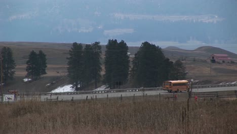 A-Yellow-School-Bus-Travels-Along-A-Rural-Road-To-Pick-Up-Its-Passengers