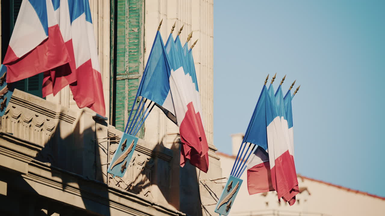 Wide shot of a historic building decorated with French tricolor flags under clear daylight