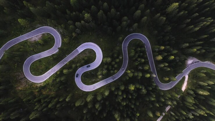 Cars driving on a curvy road, in Dolomites, Italy - Birds eye, drone shot