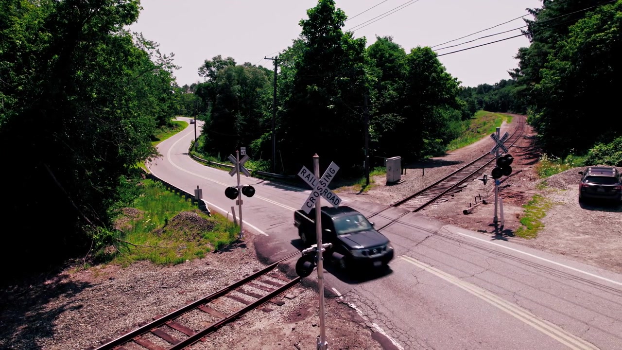 Passenger vehicles pass over a rail road crossing on a summer day in Boylston, Massachusetts.