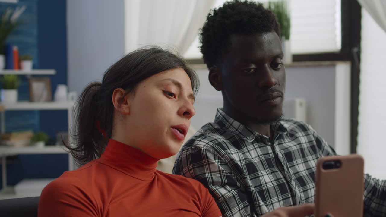 Close up of mixed race couple using smartphone at home