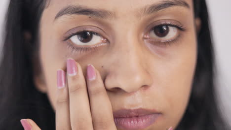 periorbital dark circle, insomnia, a young lady showing her under eye dark circle in white background, close up shot.