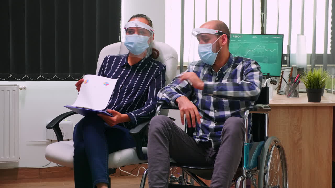Disabled man and partner with masks having videomeeting