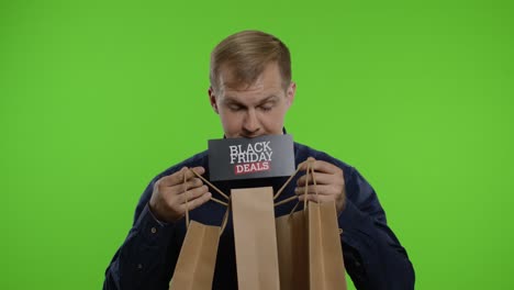 surprised man showing shopping bags and black friday deals inscription in his mouth. chroma key