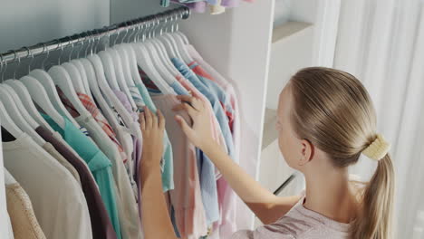 A-teenager-chooses-a-dress-in-the-dressing-room.-Top-view