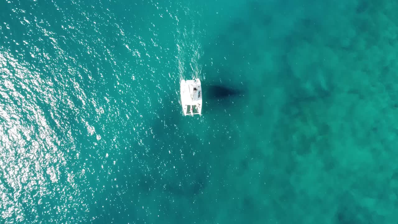 una vista de pájaro de un velero catamarán blanco solitario navegando en las tranquilas aguas turquesas del océano frente a la costa de españa