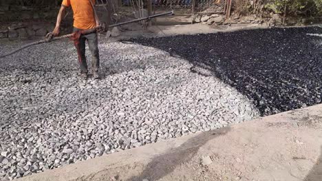 a closeup video shot of workers arranging asphalt road or damar road constructions - worker spraying asphalt on the city road in india