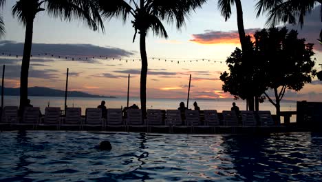 a man is swimming in the pool at sunset