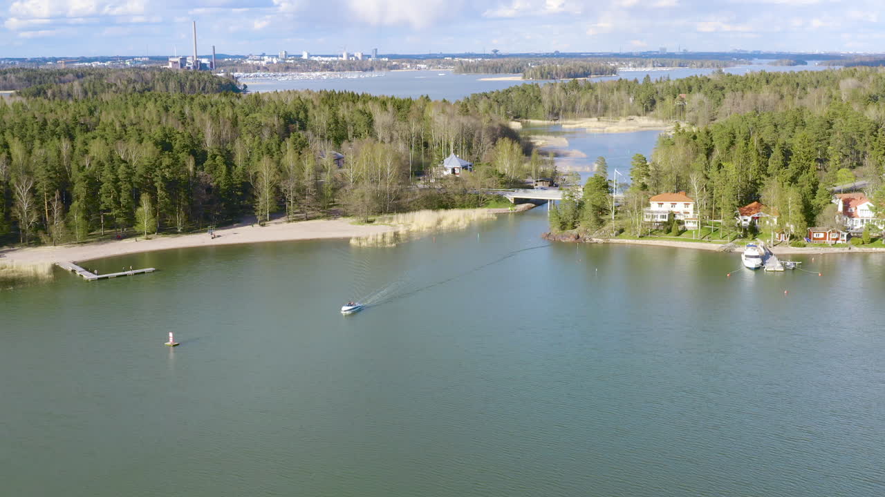 Lowering towards the shore of a beautiful lake as a boat passes underneath the startling blue waters and green trees can be seen