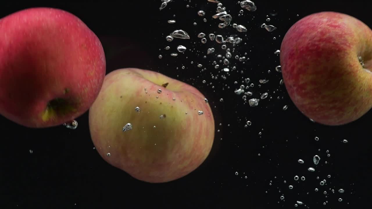 검은 바탕에 물에 떨어지는 세 개의 사과