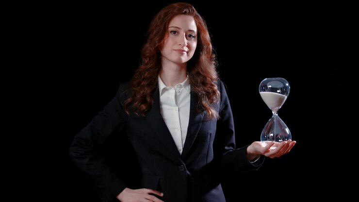 A caucasian businesswoman points at an hour glass and shakes her head