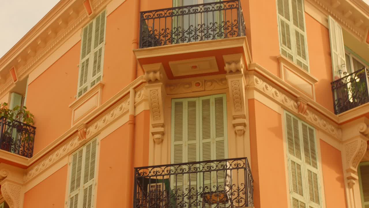 Condominio nel centro storico di Monaco con un esterno vivace giallo-arancio e molteplici finestre con persiane a lamelle verde chiaro. - Ripresa in tilt-down.