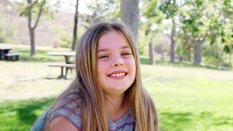 slow motion portrait of young girl with backpack in park smiling at camera