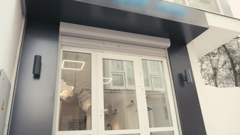 young professional businesswoman comes out of the door of cafe or salon and happy smiles into camera