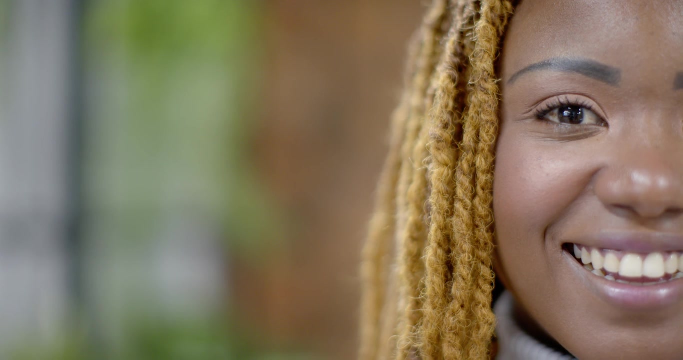 African American woman with dreadlocks in turtleneck after blink opening eye, smiling near window