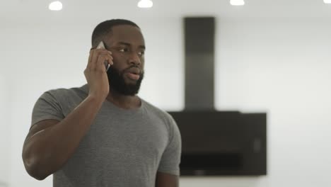 Angry-black-man-talking-phone-at-home.-Young-guy-listening-cellphone.