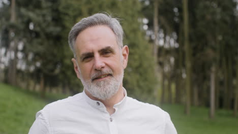 portrait of a gray haired man standing in the park and looking at the camera 3