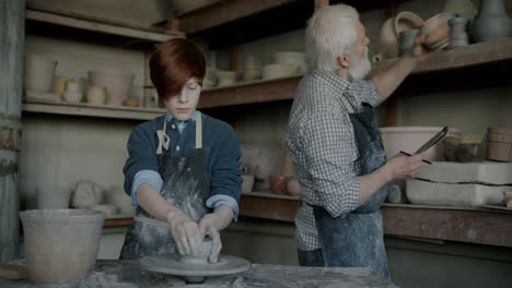 young apprentice learning pottery from experienced master