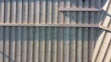 Sustainable-natural-wooden-roof-made-from-planks-on-top-of-hut-in-Myrkdalen-Norway---Birdseye-aerial-moving-left-above-rooftop-during-sunrise