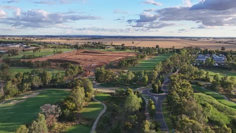 Antena-De-La-Tarde-Del-Campo-De-Golf-Black-Bull-Y-Zona-De-Construcción-De-Casas-Nuevas-Con-Tierras-De-Cultivo-Más-Allá