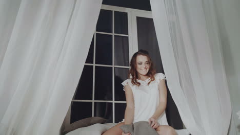 woman relaxing by window in bedroom