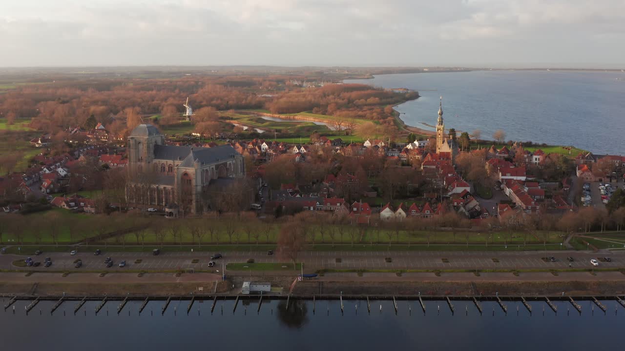 Historical city Veere with the big church and city hall tower with in the foreground the canal through Walcheren, during sunset. Drone shot
