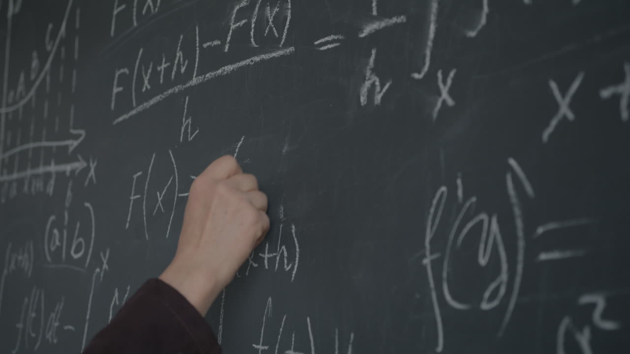 Person writing equations on a chalkboard