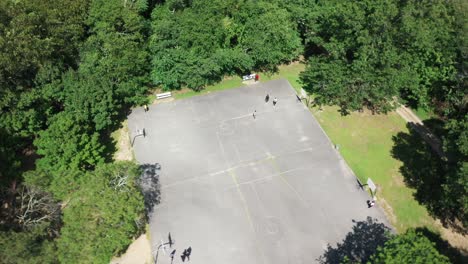 an aerial view over people playing basketball on a court is surrounded by beautiful green trees