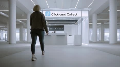 a woman approaches a click-and-collect booth in a modern, spacious building