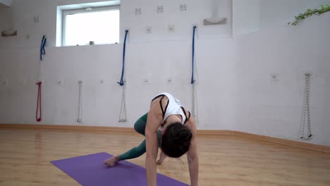 flexible woman performing three legged downward facing dog pose indoors