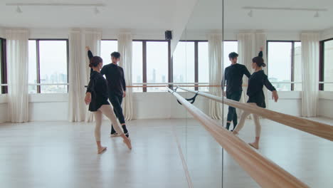 young ballet couple performing synchronic moves in dance studio