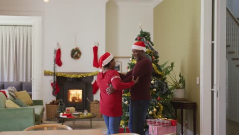Glückliches-älteres-Afroamerikanisches-Paar-Tanzt-Im-Wohnzimmer-Mit-Weihnachtsbaum