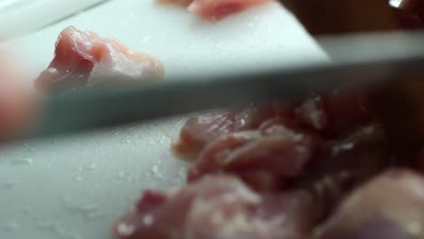 person hand cutting chicken meat close up ,