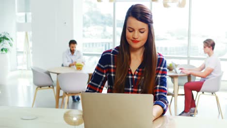 ejecutiva sentada en un escritorio y usando una computadora portátil
