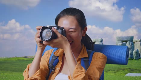 close up of asian female hiker with mountaineering backpack using a camera taking picture while traveling in stonehenge