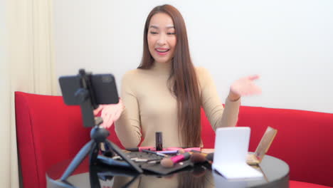 asian woman infuencer vlogging on her social networks about makeup and skincare products using smartphone, static slow motion