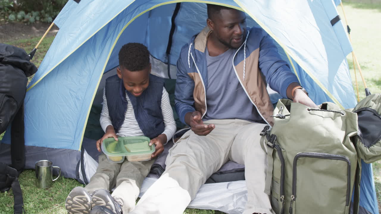 padre y hijo afroamericanos disfrutan de acampar al aire libre