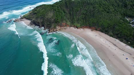 ocean waves splashing on sandy shore of broken head beach in new south wales, australia - aerial drone shot