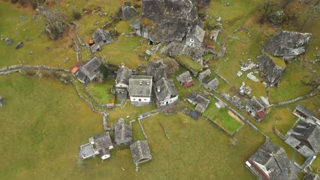 Overhead-drone-shot-retreating-to-reveal-the-whole-community-of-stone-houses-in-Cavergno-Village,-located-in-the-district-of-Vallemaggia,-in-Switzerland