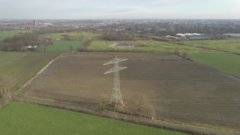 jib down of large electricity transmission towers in countryside with a city in the background