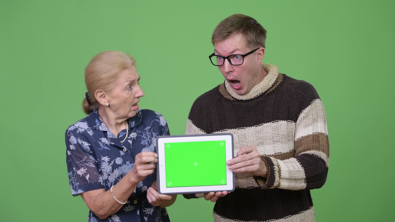 Grandmother and grandson showing digital tablet and looking shocked together